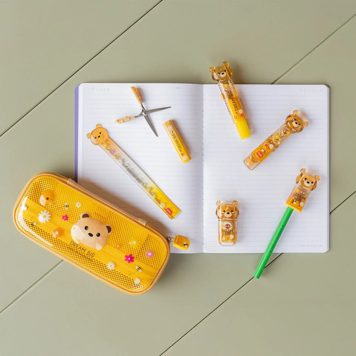 Überblick der Bear Sweet Bear Kollektion von Legami mit Mäppchen, Korrekturroller, Kleberoller, Schere und Lineal auf einem aufgeschlagenen Notizbuch