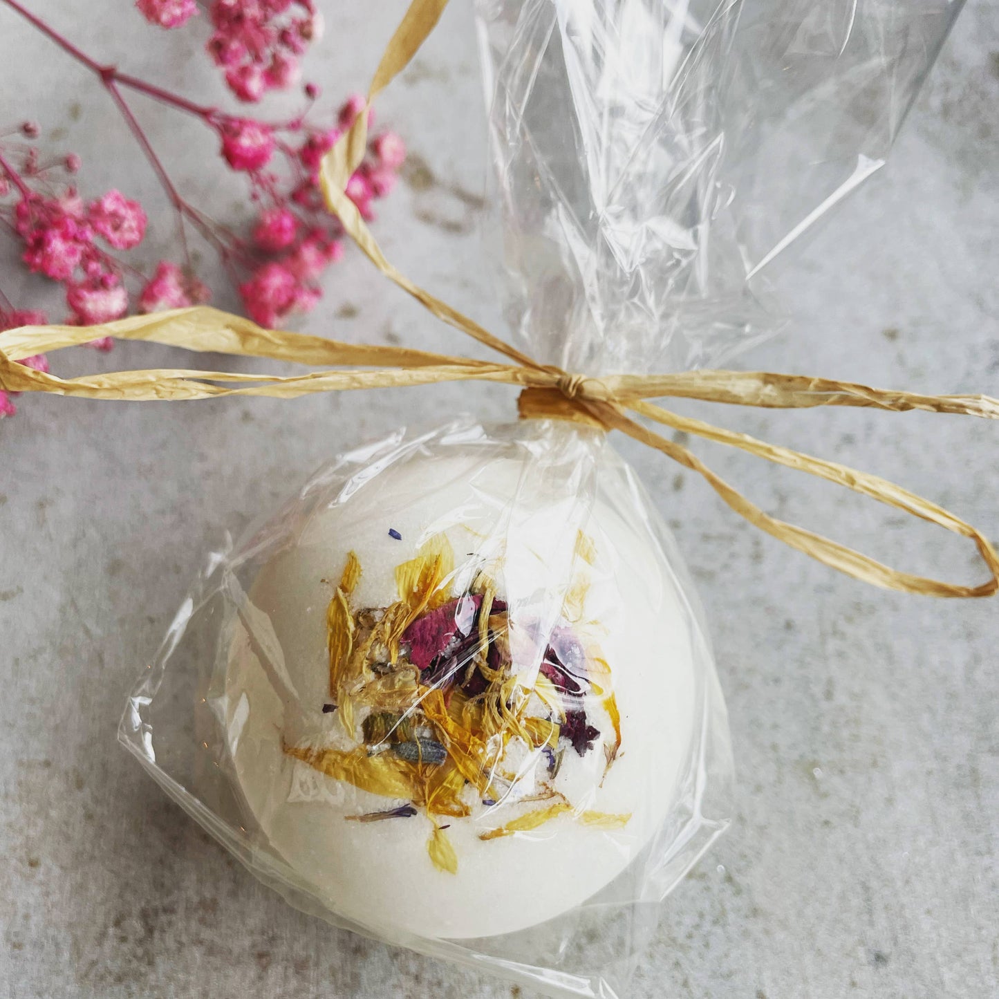 Handgefertigte Badekugel „Blütenmix" mit Bio-Sheabutter, Mandelöl und getrockneten Blüten aus Lavendel, Kornblume, Ringelblume und Rosenblättern, verpackt in biologisch abbaubarem Zellglas mit Strohband – pflegendes Spa-Erlebnis für Zuhause