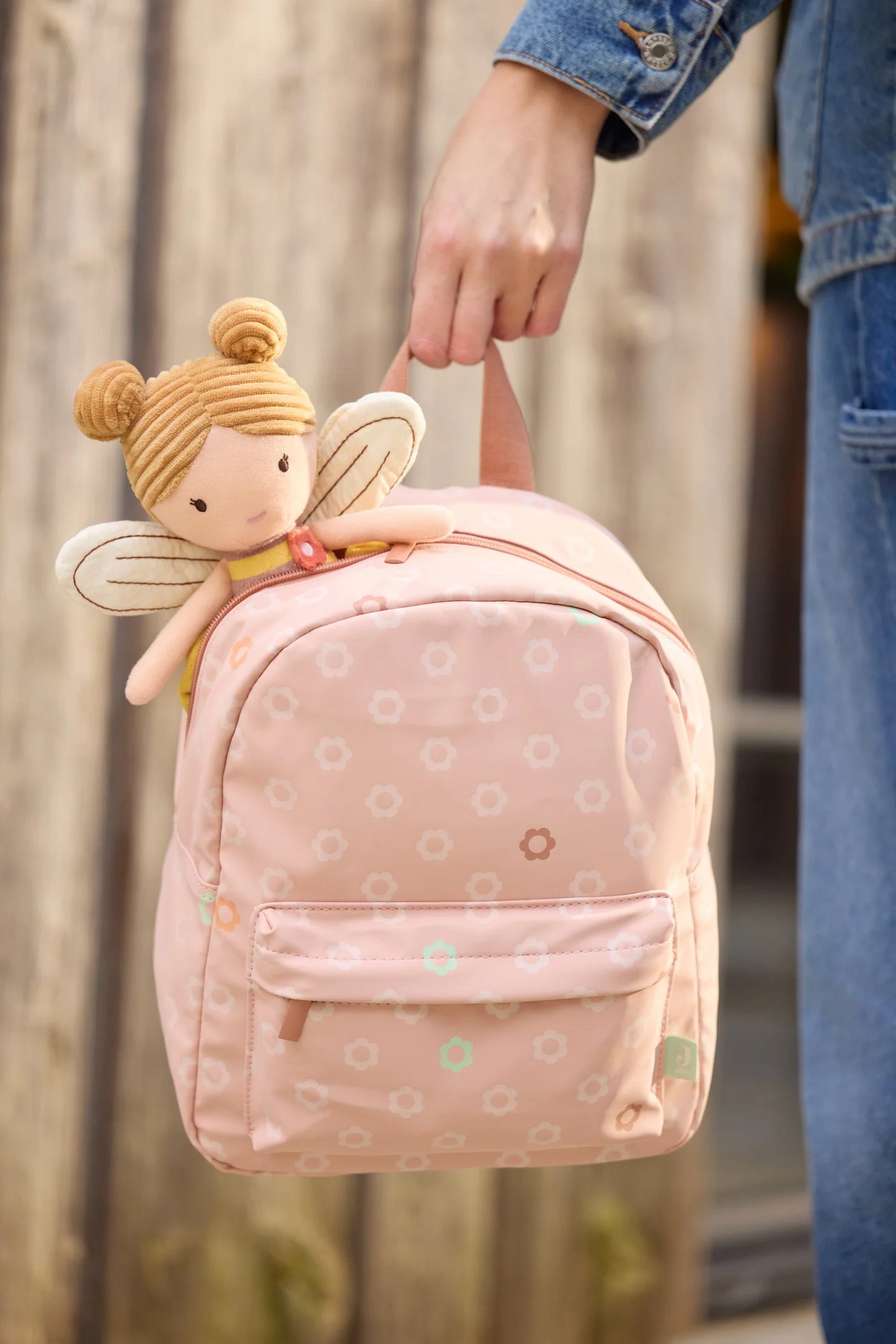 Jollein Stoffpuppe „Bee Lily" im Bienen-Outfit mit Flügeln schaut aus einem rosa Kinderrucksack – Lifestyle-Aufnahme bei Burgfrollein
