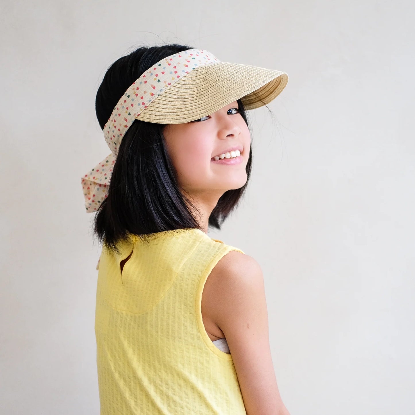 Mädchen trägt sommerliche Sonnenvisier-Mütze Heart Print Visor mit Herz-Motiv von Mimi & Lula – stylische Stroh-Sonnenblende für Kinder