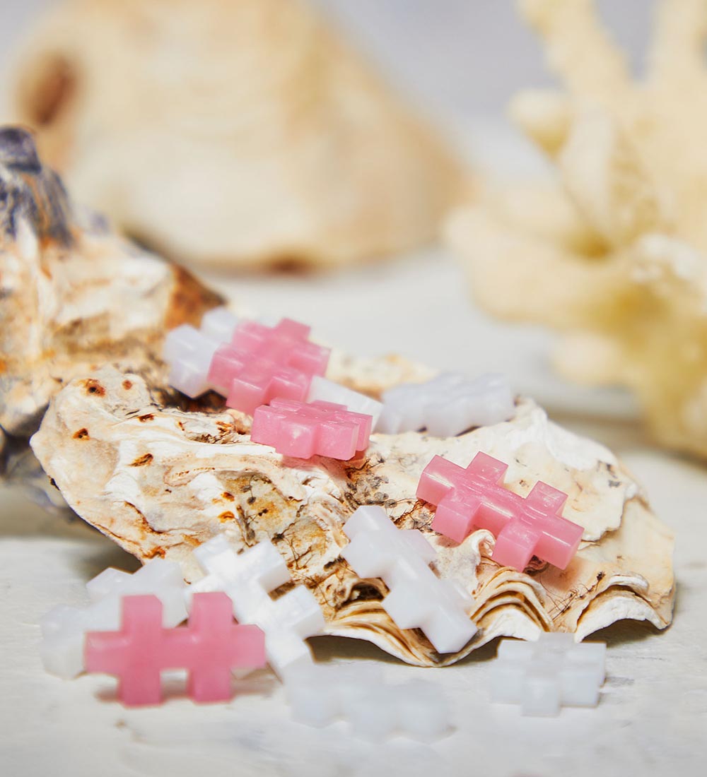 Nahaufnahme der Plus-Plus Pearl Bausteine in Rosa und Weiß mit zartem Perlmutt-Glanz auf einer Muschel