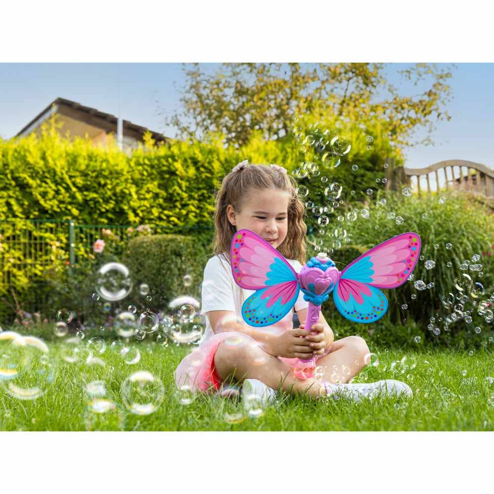 Pustefix Seifenblasenpistole als Schmetterling mit Sound und Licht – Mädchen sitzt im Garten und spielt fröhlich mit der Schmetterlings-Seifenblasenmaschine, umgeben von vielen Seifenblasen