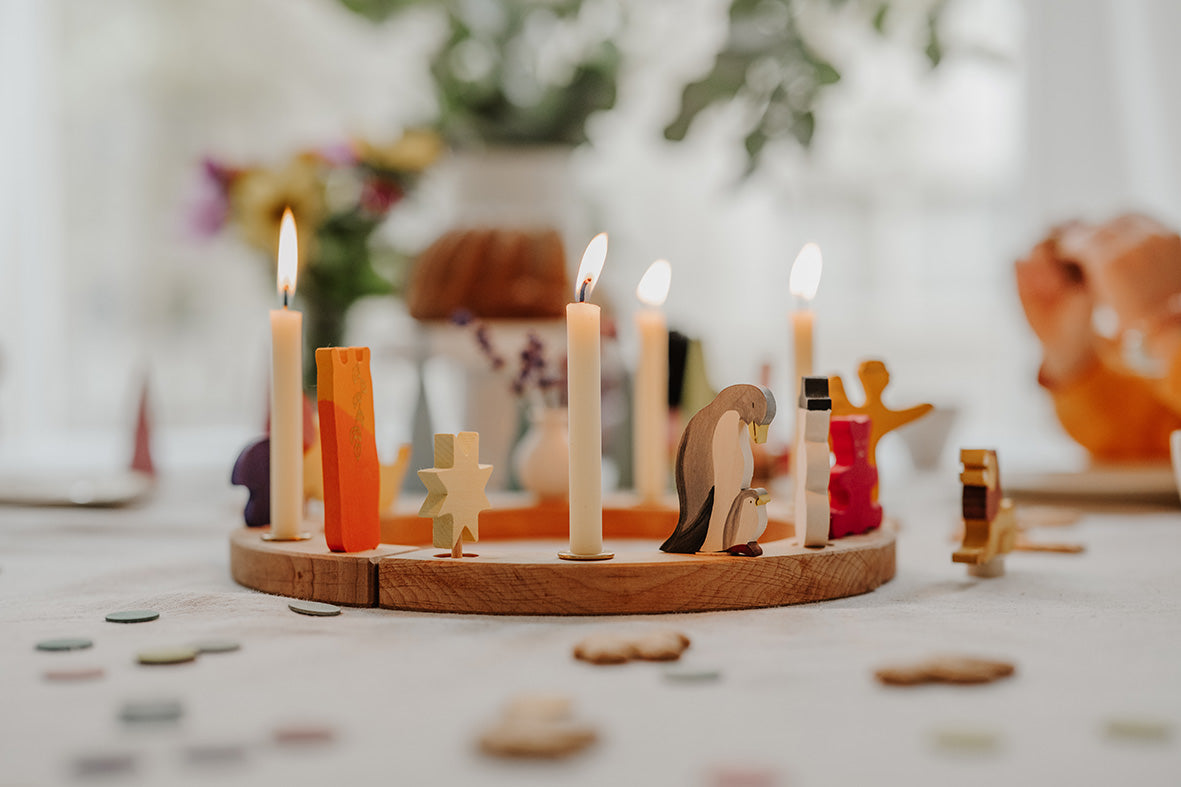 Grimms Festtagsring mit Bienenwachskerzen, dekoriert mit Pinguin- und Stern-Holzfigur - Beispiel für die festliche Tischdekoration