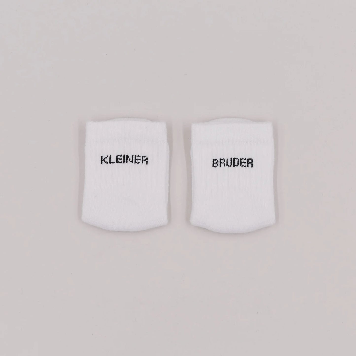Eulenschnitt Baby-Socken „Kleiner Bruder" in Weiß, Größe 16-18, Hauptproduktbild auf neutralem Hintergrund bei Burgfrollein