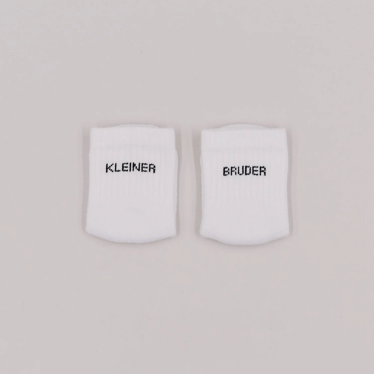 Eulenschnitt Baby-Socken „Kleiner Bruder" in Weiß, Größe 16-18, Hauptproduktbild auf neutralem Hintergrund bei Burgfrollein