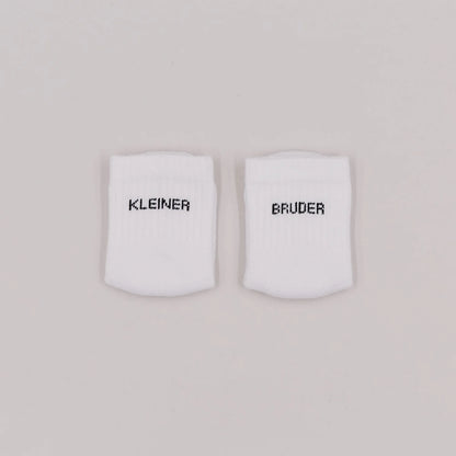 Eulenschnitt Baby-Socken „Kleiner Bruder" in Weiß, Größe 16-18, Hauptproduktbild auf neutralem Hintergrund bei Burgfrollein