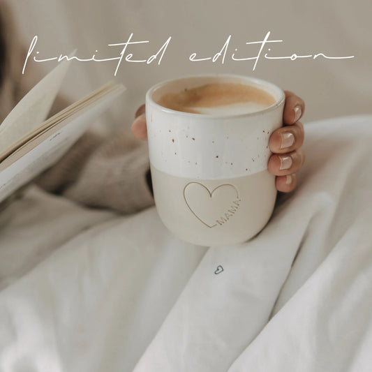 Eulenschnitt Mama Becher mit Herz-Prägung gefüllt mit Kaffee neben Buch – limited edition Muttertagsgeschenk