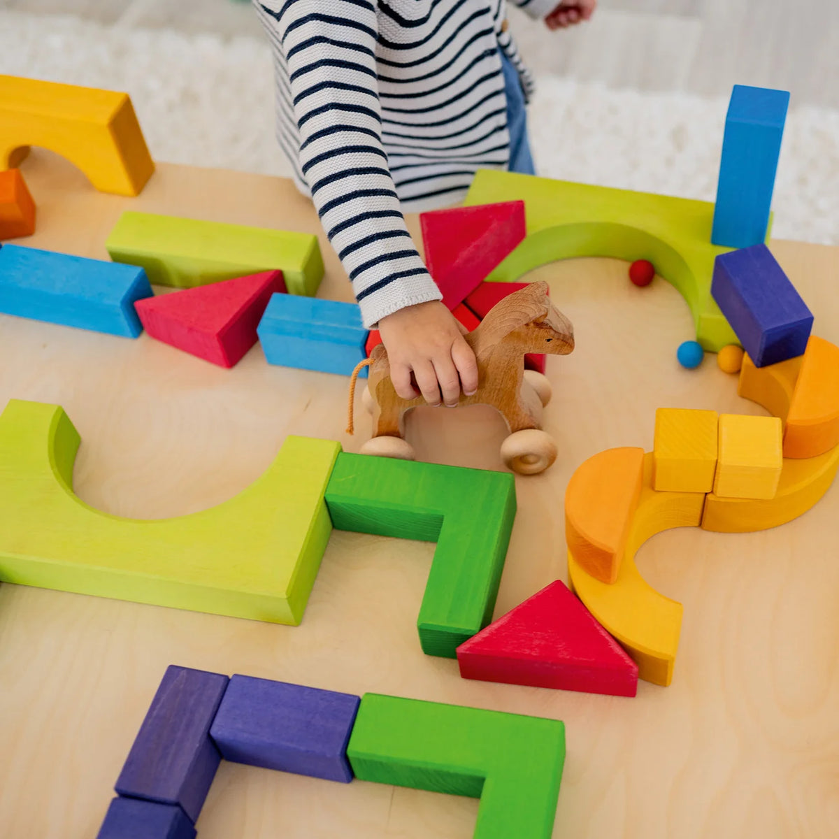 Kind spielt mit den Bausteinen des Grundbaukasten 1 von Grimm's – Geschenkidee ab 3 Jahren