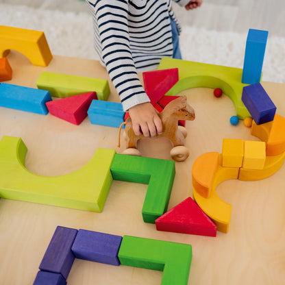 Kind spielt mit den Bausteinen des Grundbaukasten 1 von Grimm's – Geschenkidee ab 3 Jahren