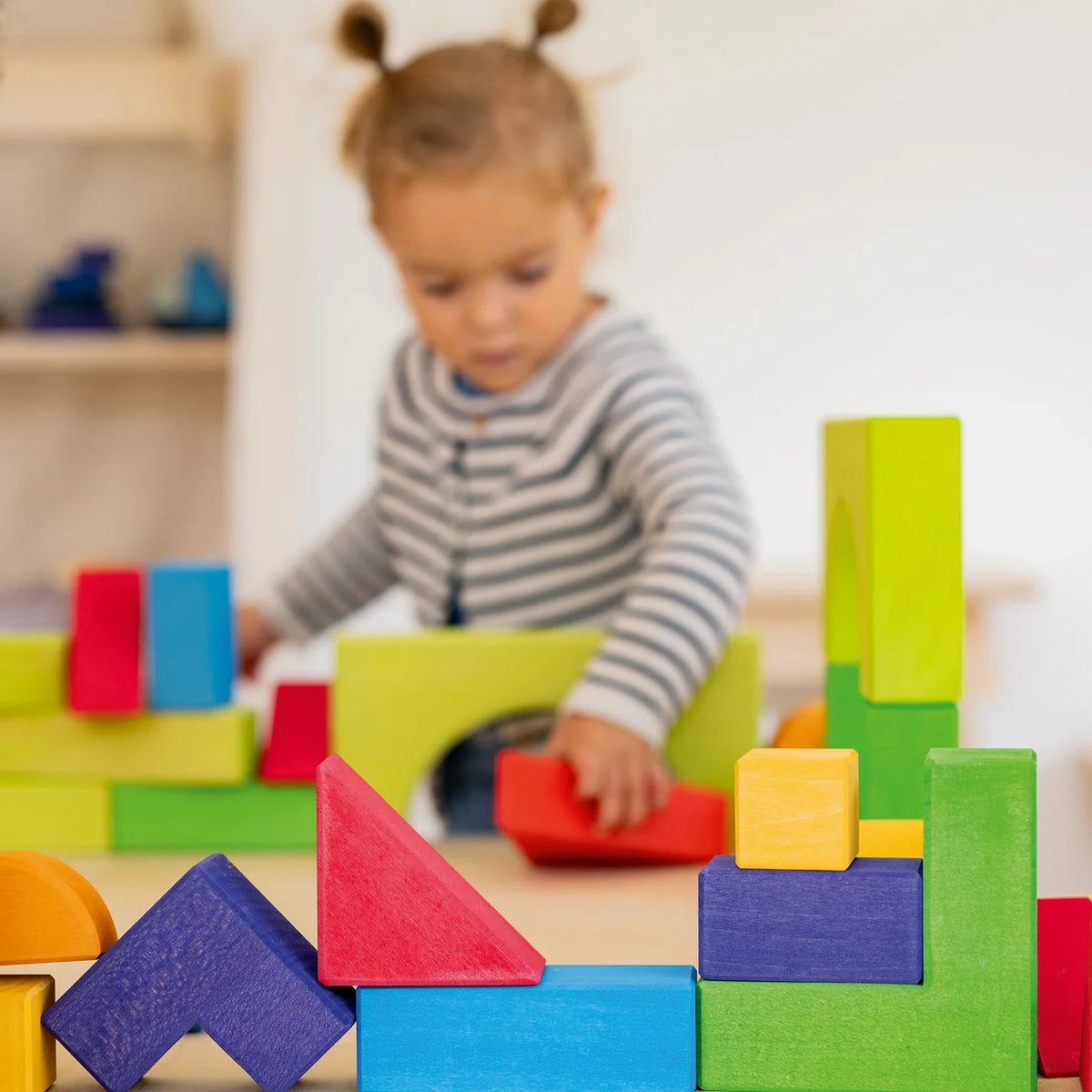 Kind baut einen Turm mit dem Grundbaukasten 1 von Grimm's – Montessori Waldorf Holzspielzeug ab 3 Jahren