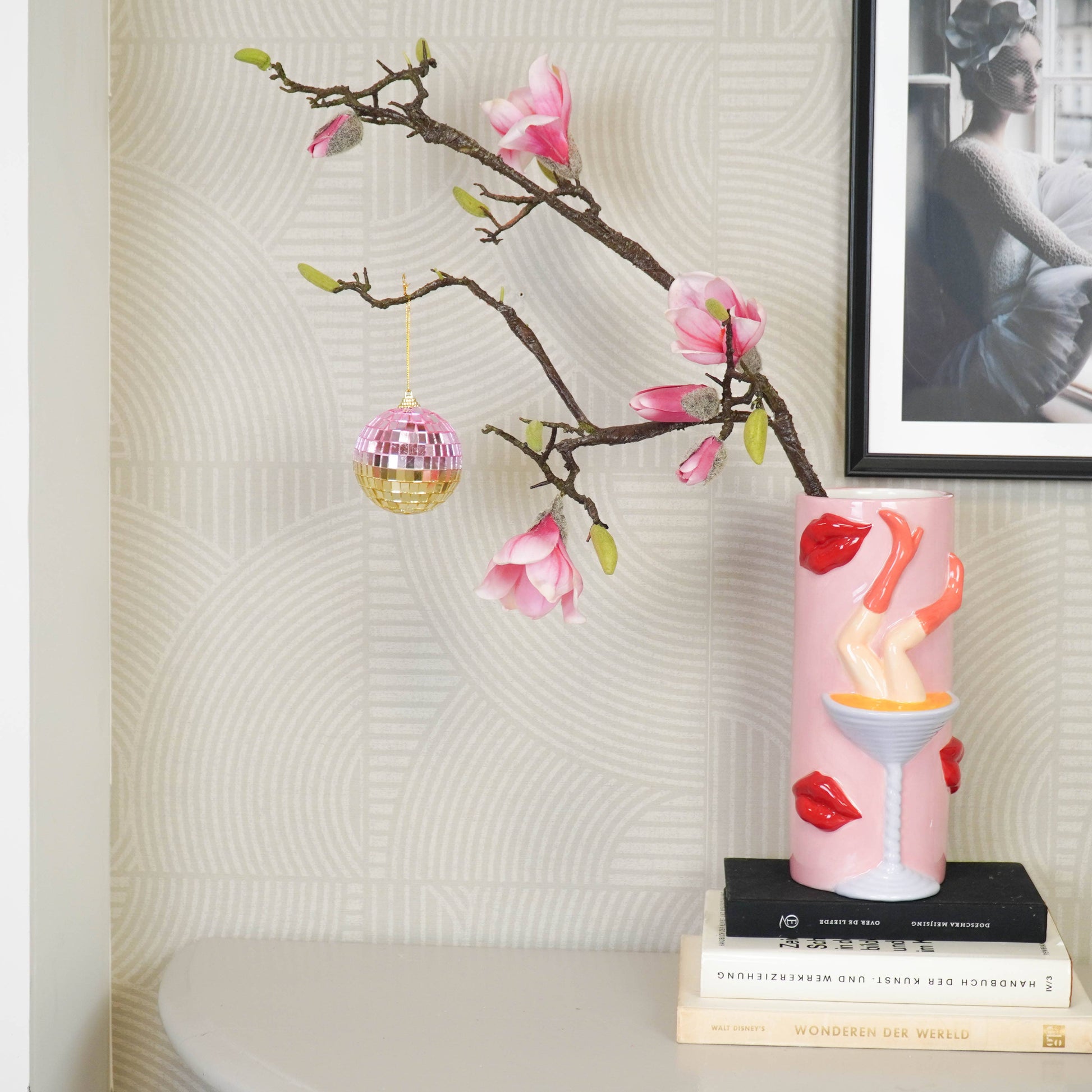 Discokugel für gute Laune von House Vitamin, 8 cm, in Rosa- und Goldtönen hängend an einem Magnolienzweig im stilvollen Wohnzimmer-Setting mit Büchern und Wandbild – funkelnde Wohnungsdeko und stimmungsvolle Geschenkidee