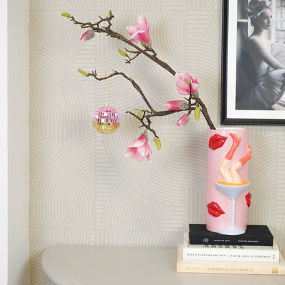 Discokugel für gute Laune von House Vitamin, 8 cm, in Rosa- und Goldtönen hängend an einem Magnolienzweig im stilvollen Wohnzimmer-Setting mit Büchern und Wandbild – funkelnde Wohnungsdeko und stimmungsvolle Geschenkidee