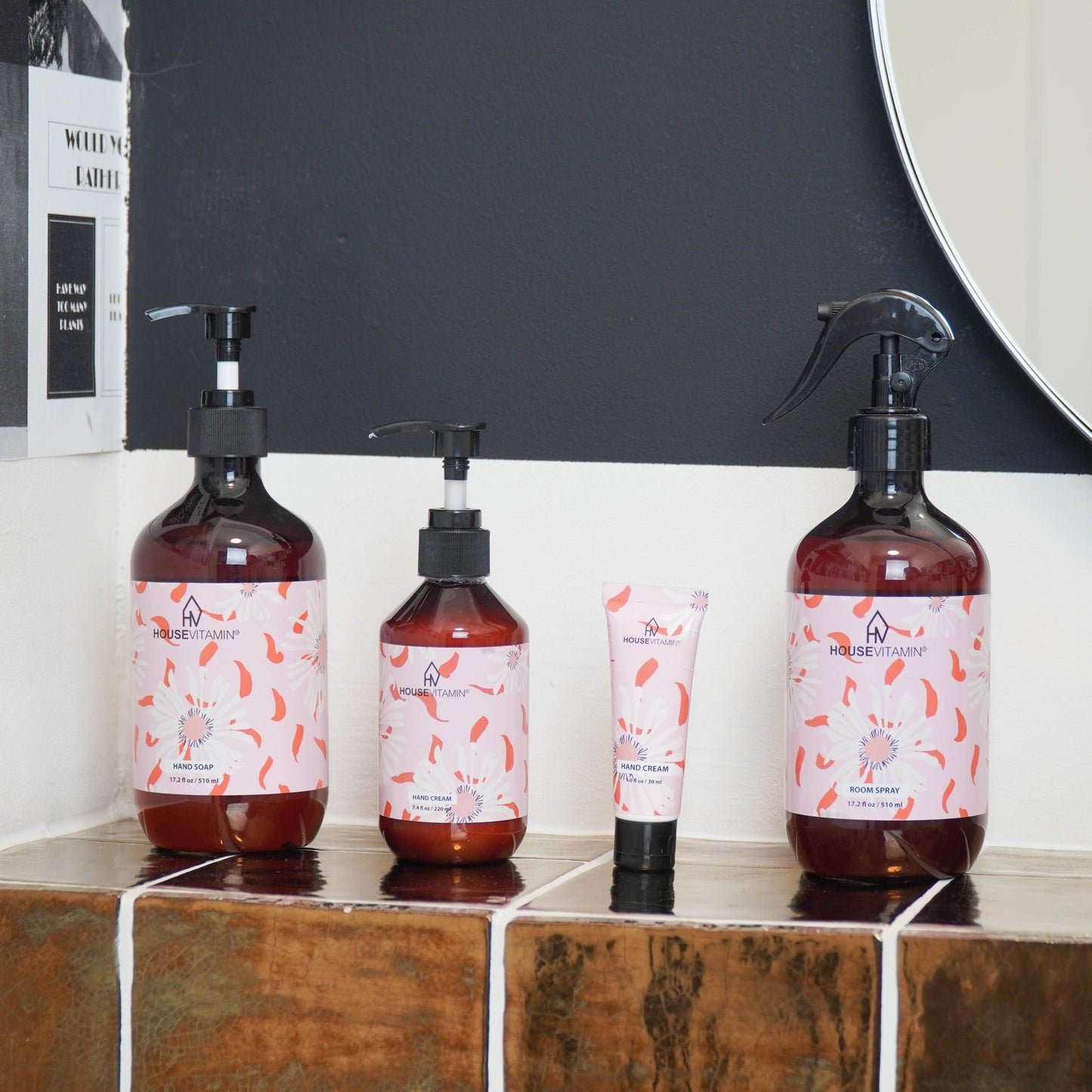 Kleine Tube Handcreme „Pfingstrosenblüte" von House Vitamin, 30 ml, neben größeren Pumpflaschen und Raumspray der Pflegeserie im stilvollen Badezimmer-Setting – florale Wellness-Linie als pflegende Geschenkidee
