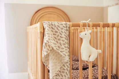 Kuschelige Lama-Spieluhr von Jollein am Gitterbett im natürlichen Kinderzimmer – ideal als Babyparty-Geschenk