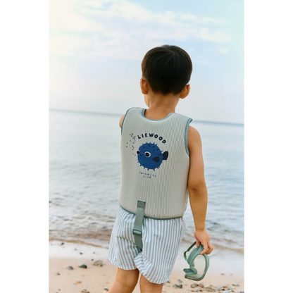 Kind am Strand von hinten mit Liewood Schwimmweste in Mint gestreift mit Kugelfisch-Print und Logo bei Burgfrollein