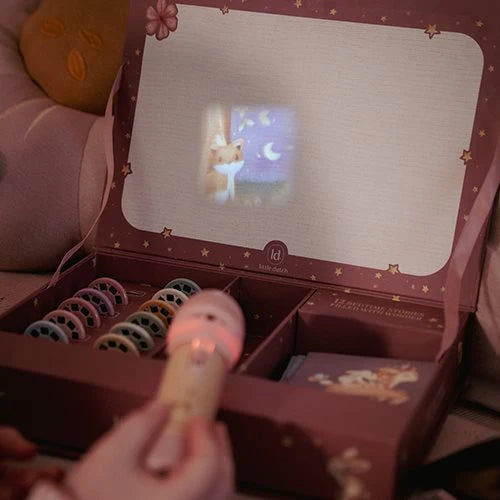 Little Dutch Geschichten-Taschenlampe aus der Fairy Garden Kollektion in Rosa projiziert ein Bild in den Deckel der geöffneten rosa Geschenkbox mit Diascheiben und Geschichtenheften