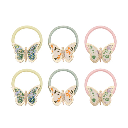 Haargummis mit Schmetterling-Motiv von Mimi & Lula, 6er Set in Pastelltönen Gelb, Mint und Rosa mit floral gemusterten Stoff-Schmetterlingen, aufgereiht und freigestellt vor weißem Hintergrund – frühlingshafter Haarschmuck für Kinder und liebevolle Geschenkidee