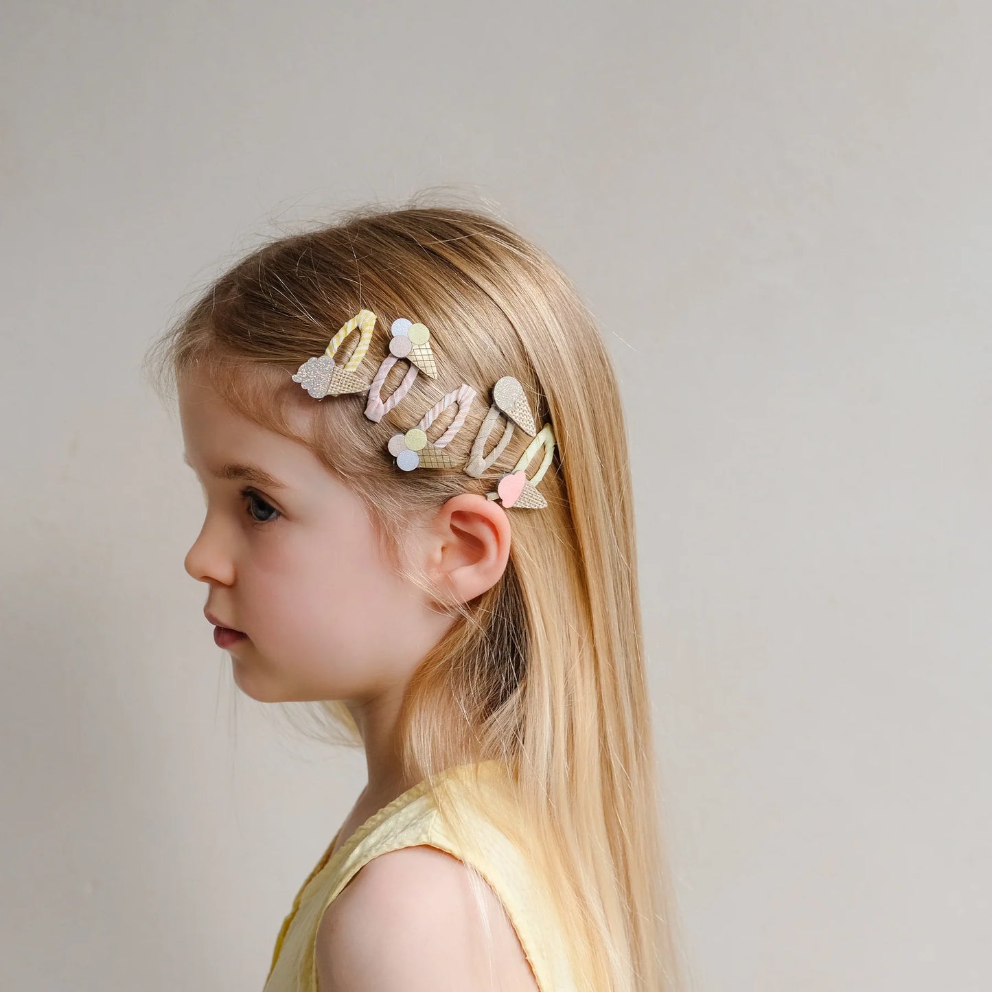 Haarspangen mit Eis-Motiv von Mimi & Lula, 5er Set in Pastelltönen wie Creme, Rosa und Gelb mit Eistüten- und Eis-am-Stiel-Motiven, getragen im Haar eines Kindes – kinderfreundlicher Haarschmuck und liebevolle Geschenkidee