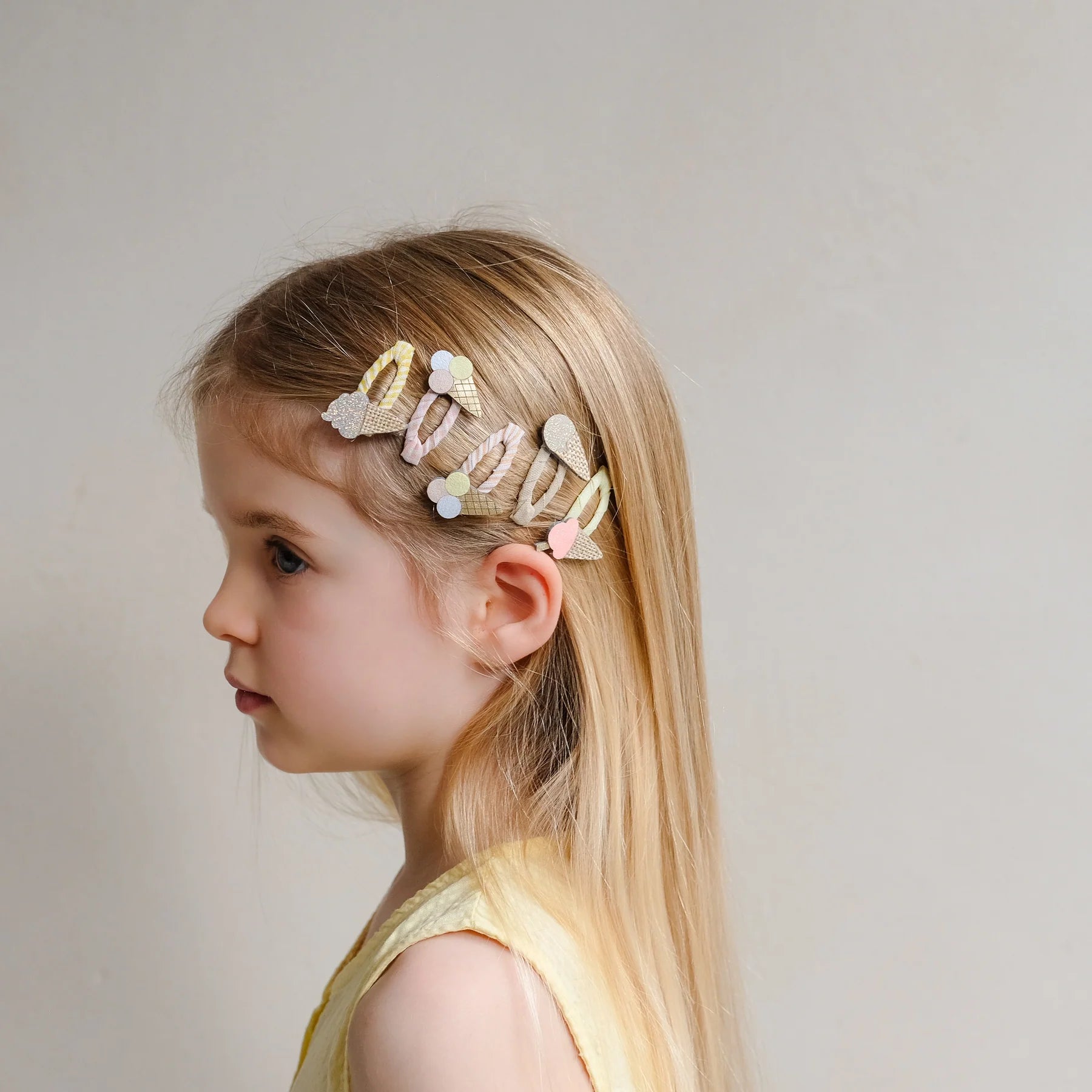Haarspangen mit Eis-Motiv von Mimi & Lula, 5er Set in Pastelltönen wie Creme, Rosa und Gelb mit Eistüten- und Eis-am-Stiel-Motiven, getragen im Haar eines Kindes – kinderfreundlicher Haarschmuck und liebevolle Geschenkidee