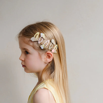 Haarspangen mit Eis-Motiv von Mimi & Lula, 5er Set in Pastelltönen wie Creme, Rosa und Gelb mit Eistüten- und Eis-am-Stiel-Motiven, getragen im Haar eines Kindes – kinderfreundlicher Haarschmuck und liebevolle Geschenkidee