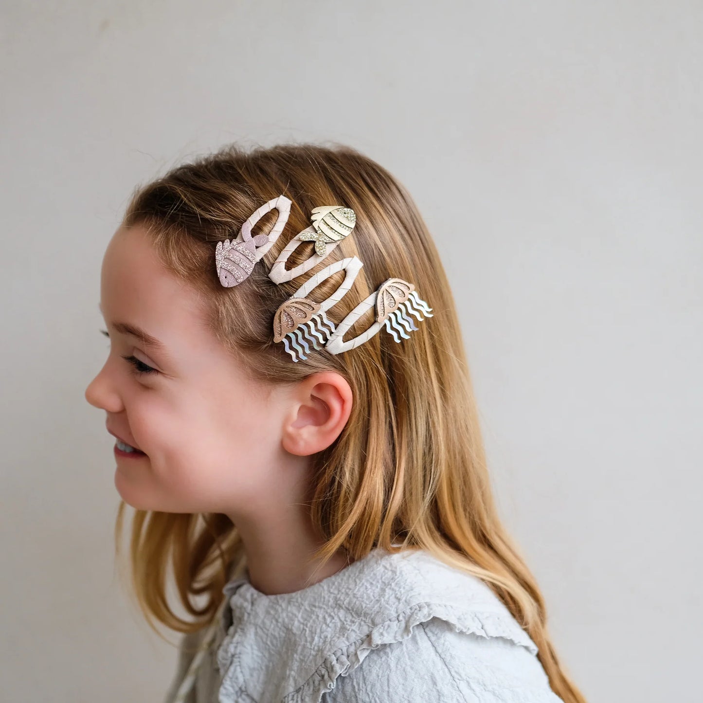 Haarspangen mit Fisch-Motiv von Mimi & Lula, 4er Set mit zwei Fischen und zwei Quallen in Creme- und Rosatönen mit Glitzer-Details, getragen im Haar eines Kindes vor hellem Hintergrund – kinderfreundlicher Haarschmuck und liebevolle Geschenkidee