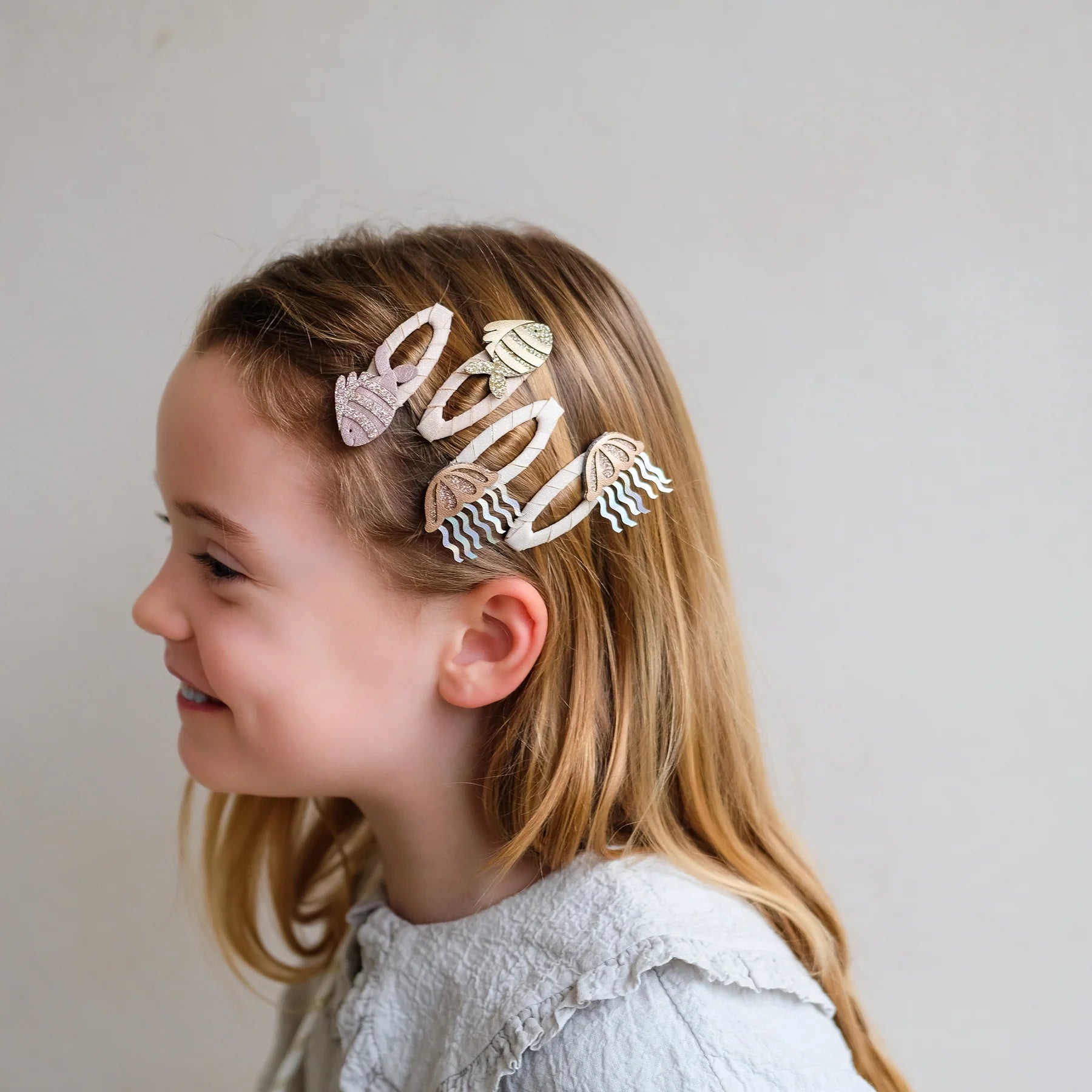 Haarspangen mit Fisch-Motiv von Mimi & Lula, 4er Set mit zwei Fischen und zwei Quallen in Creme- und Rosatönen mit Glitzer-Details, getragen im Haar eines Kindes vor hellem Hintergrund – kinderfreundlicher Haarschmuck und liebevolle Geschenkidee