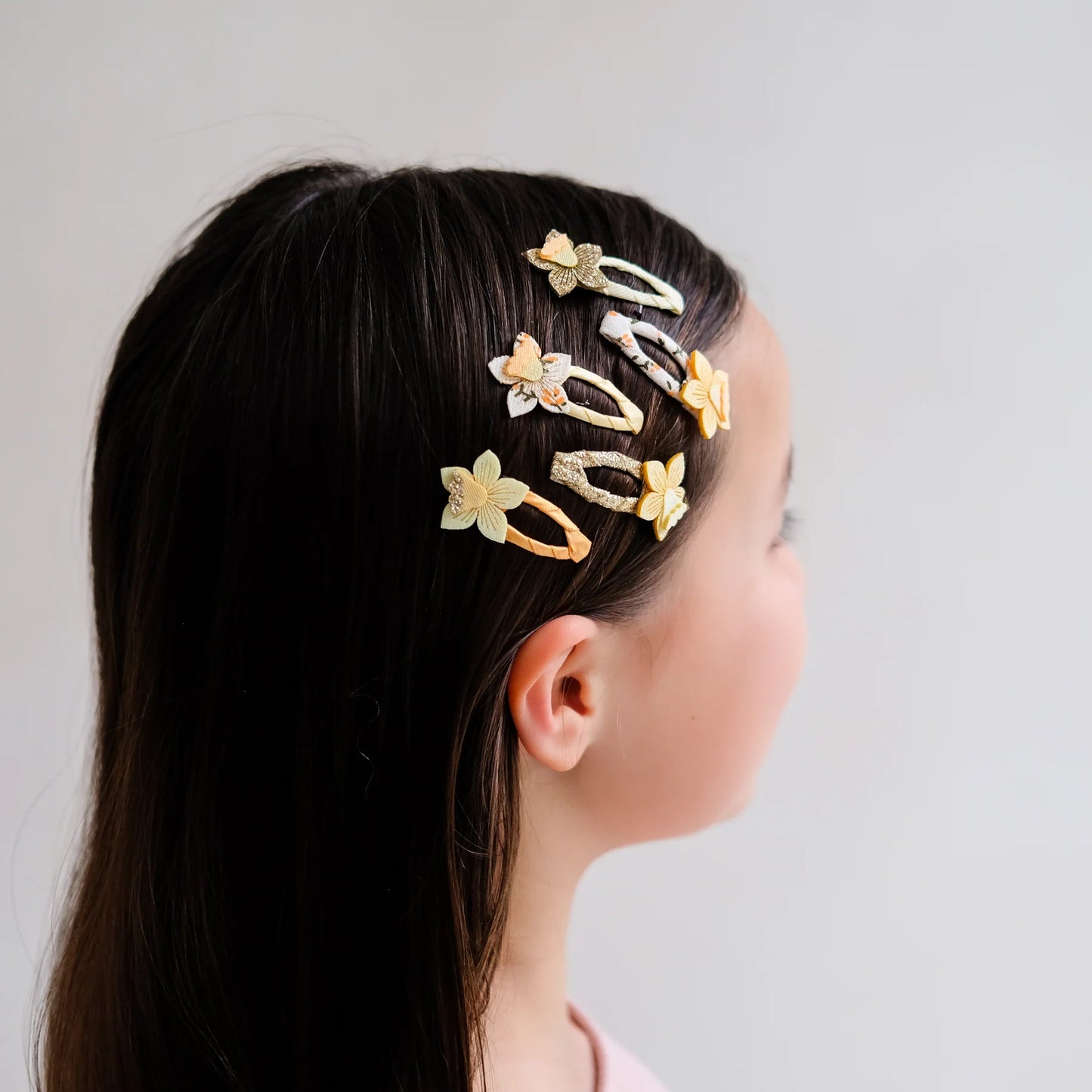 Haarspangen mit Osterglocken-Motiv von Mimi & Lula, 5er Set mit gelben und cremefarbenen Narzissen-Blüten auf Stoffspangen mit Glitzer-Details, getragen in Detailansicht im Haar eines Kindes – frühlingshafter Haarschmuck für Kinder und liebevolle Geschenkidee zu Ostern
