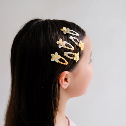Haarspangen mit Osterglocken-Motiv von Mimi & Lula, 5er Set mit gelben und cremefarbenen Narzissen-Blüten auf Stoffspangen mit Glitzer-Details, getragen in Detailansicht im Haar eines Kindes – frühlingshafter Haarschmuck für Kinder und liebevolle Geschenkidee zu Ostern