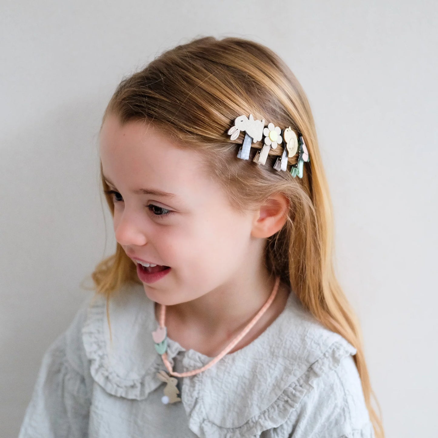 Kleine Osterhasen-Haarspangen von Mimi & Lula, 8er-Set mit Hasen, Blumen, Vögeln und Tulpen in zarten Pastelltönen, getragen im Haar eines Kindes vor hellem Hintergrund – frühlingshafter Haarschmuck für Kinder und liebevolle Geschenkidee zu Ostern