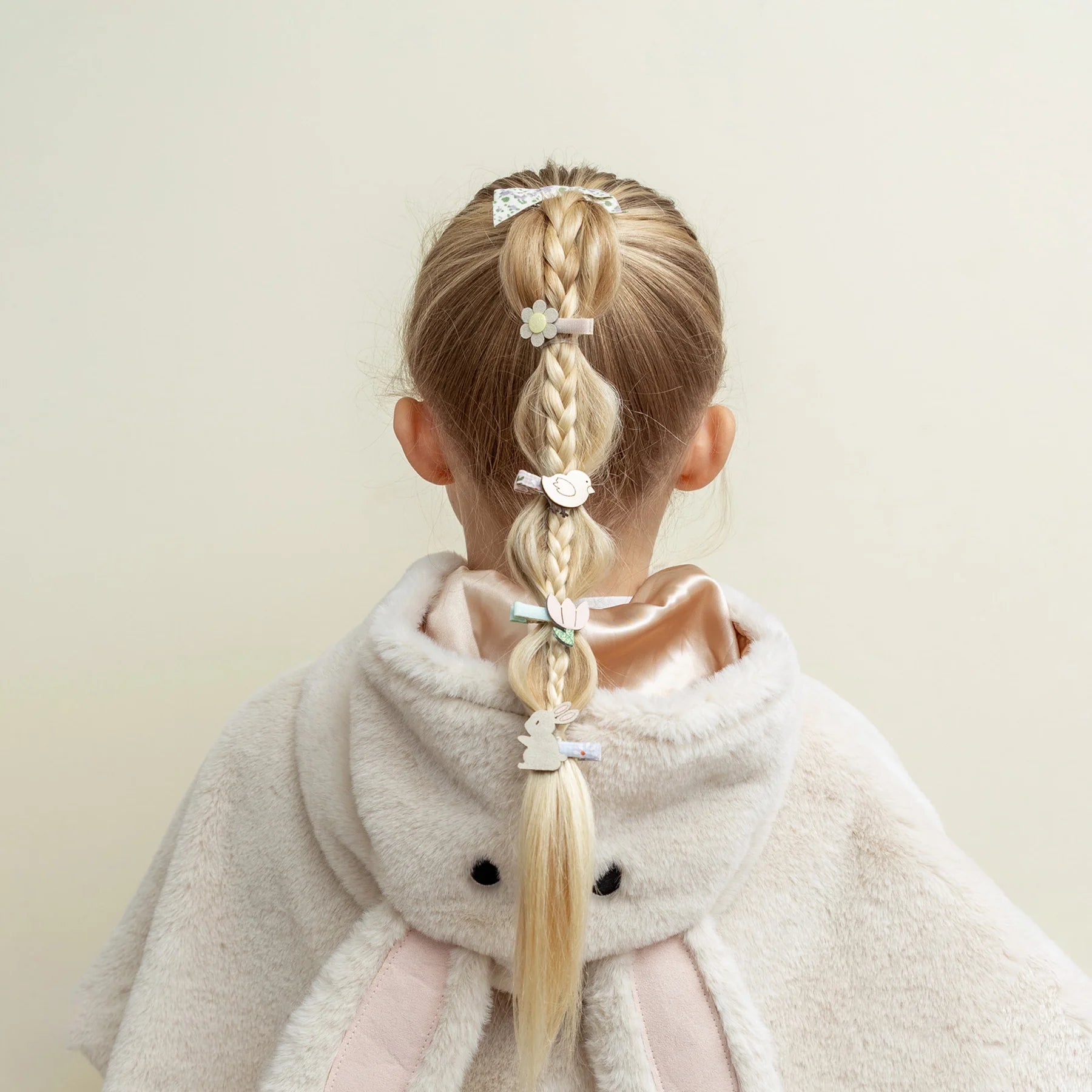 Kleine Osterhasen-Haarspangen von Mimi & Lula, 8er-Set mit Hasen, Blumen, Vögeln und Tulpen in zarten Pastelltönen, getragen entlang eines geflochtenen Zopfes eines Kindes – frühlingshafter Haarschmuck für Kinder und liebevolle Geschenkidee zu Ostern