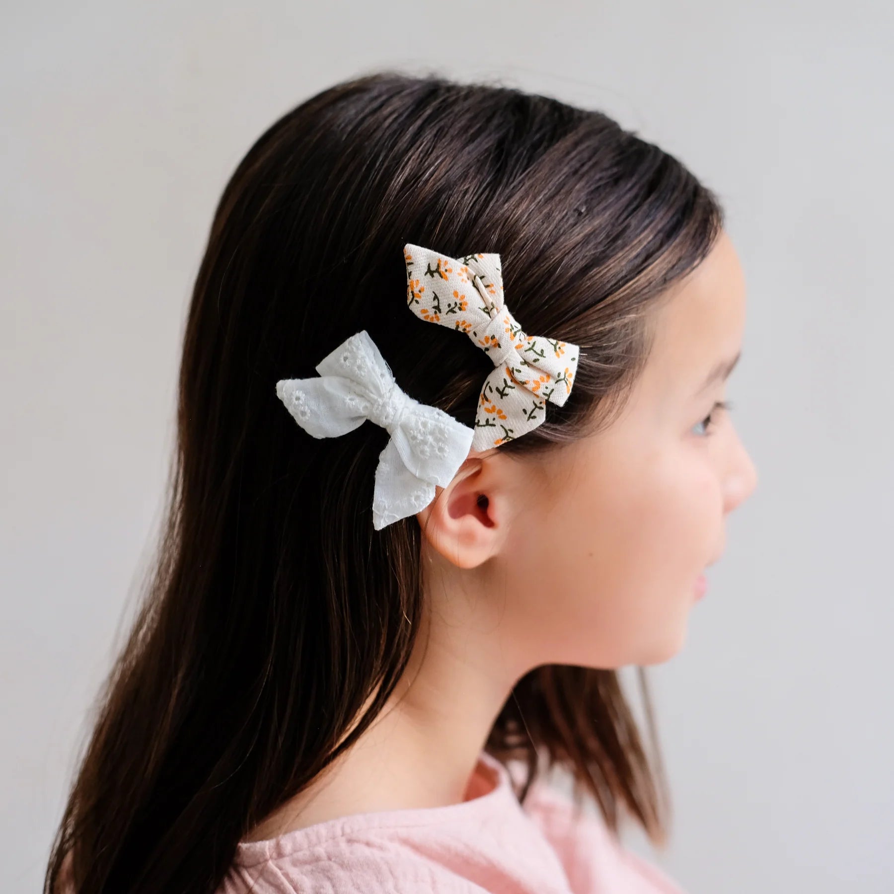 Mädchen trägt Haar-Schleifen Maggie Bow Clips von Mimi & Lula im 2er Set – stylisches Kinder-Haaraccessoire mit Blumenmuster und Lochstickerei in Creme