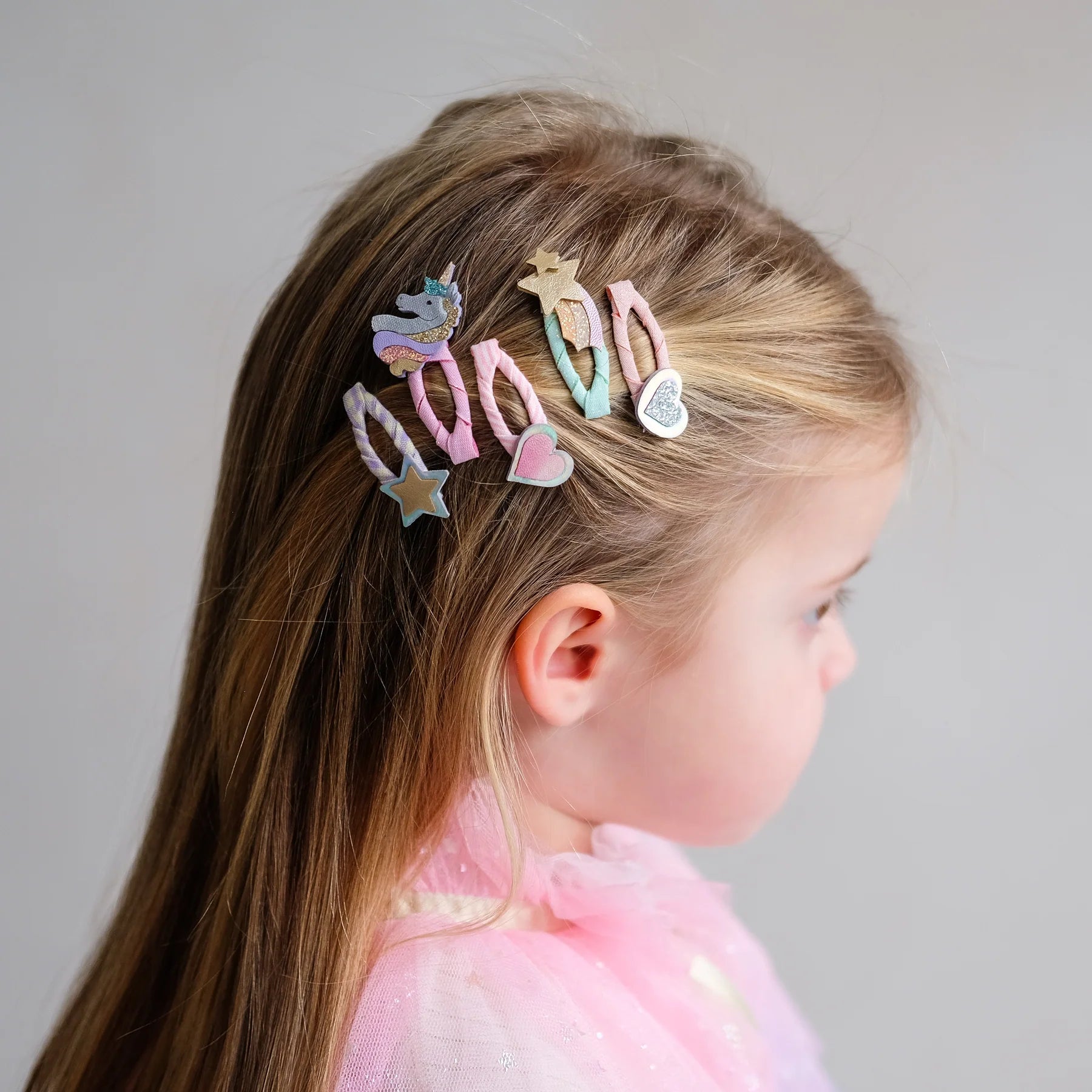 Mädchen trägt kleine Haarspangen mit Einhorn-, Stern- und Herz-Motiv von Mimi & Lula – stylisches Kinder-Haaraccessoire im 8er Set