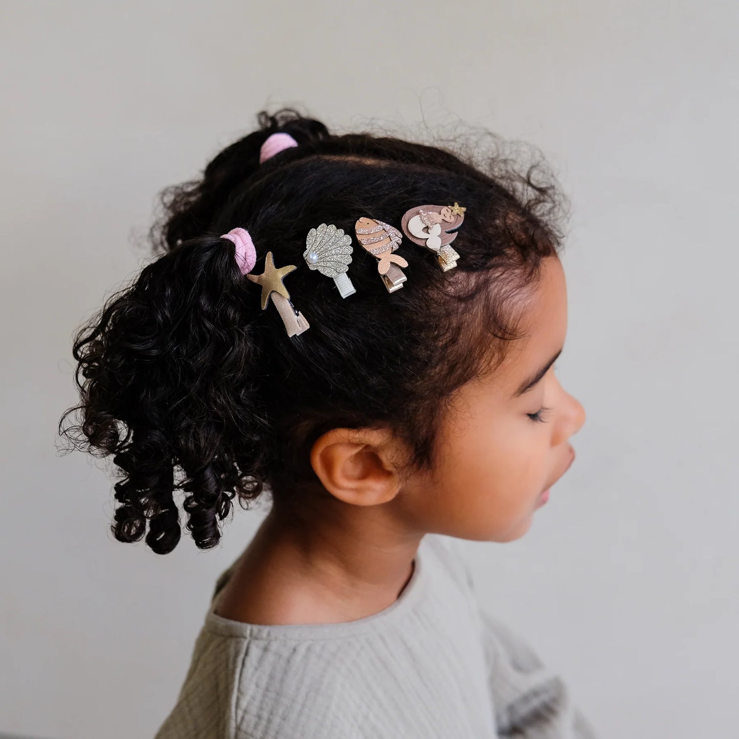 Mädchen mit Locken trägt kleine Haarspangen mit Meerjungfrauen-, Fisch-, Seestern- und Muschel-Motiv von Mimi & Lula – stylisches Kinder-Haaraccessoire im 8er Set
