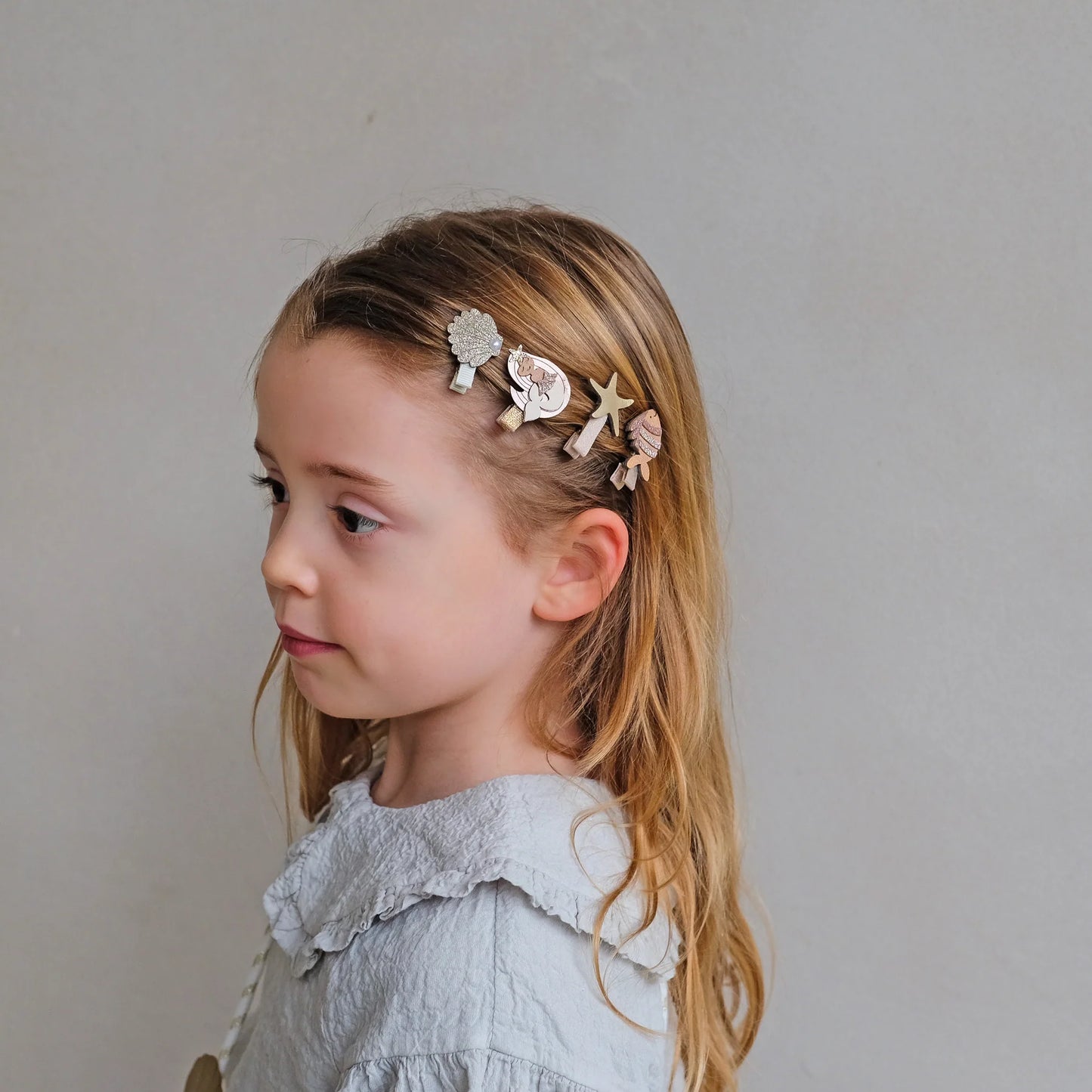 Mädchen trägt kleine Haarspangen mit Meerjungfrauen-, Fisch-, Seestern- und Muschel-Motiv von Mimi & Lula – stylisches Kinder-Haaraccessoire im 8er Set
