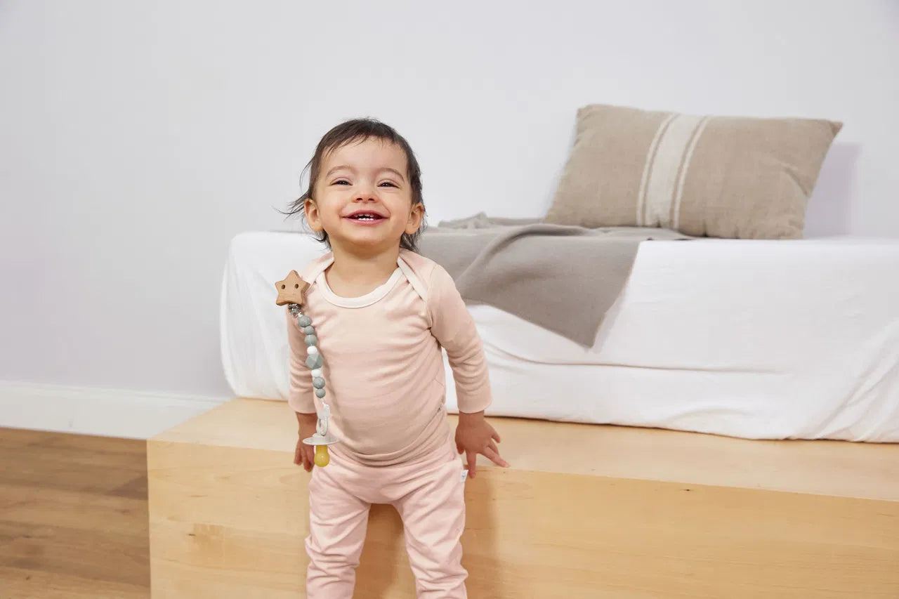 Lachendes Baby trägt mintgrüne Schnullerkette Little Universe von Lässig am Strampler