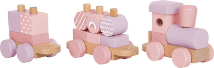 Rosa Holzzug von Small Foot in der Detailansicht mit drei Wagen – Lokomotive, mittlerer Anhänger mit Regenbogen- und Zylinder-Stapelelementen sowie Anhänger mit Herzchen-Motiv – nachhaltiges Holzspielzeug zur Förderung der Feinmotorik