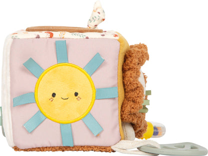 Spielwürfel „Little Lion" von Small Foot mit lächelndem Sonnenmotiv auf rosa Seite, blauen Stoffschlaufen und seitlich angebrachtem Silikon-Beißring – Babyspielzeug zur Förderung der Sinne ab 0 Monaten