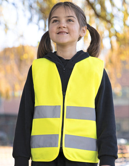 Mädchen trägt Warnweste in Neongelb mit reflektierenden Streifen – für sicheren Schulweg im Herbst und Winter