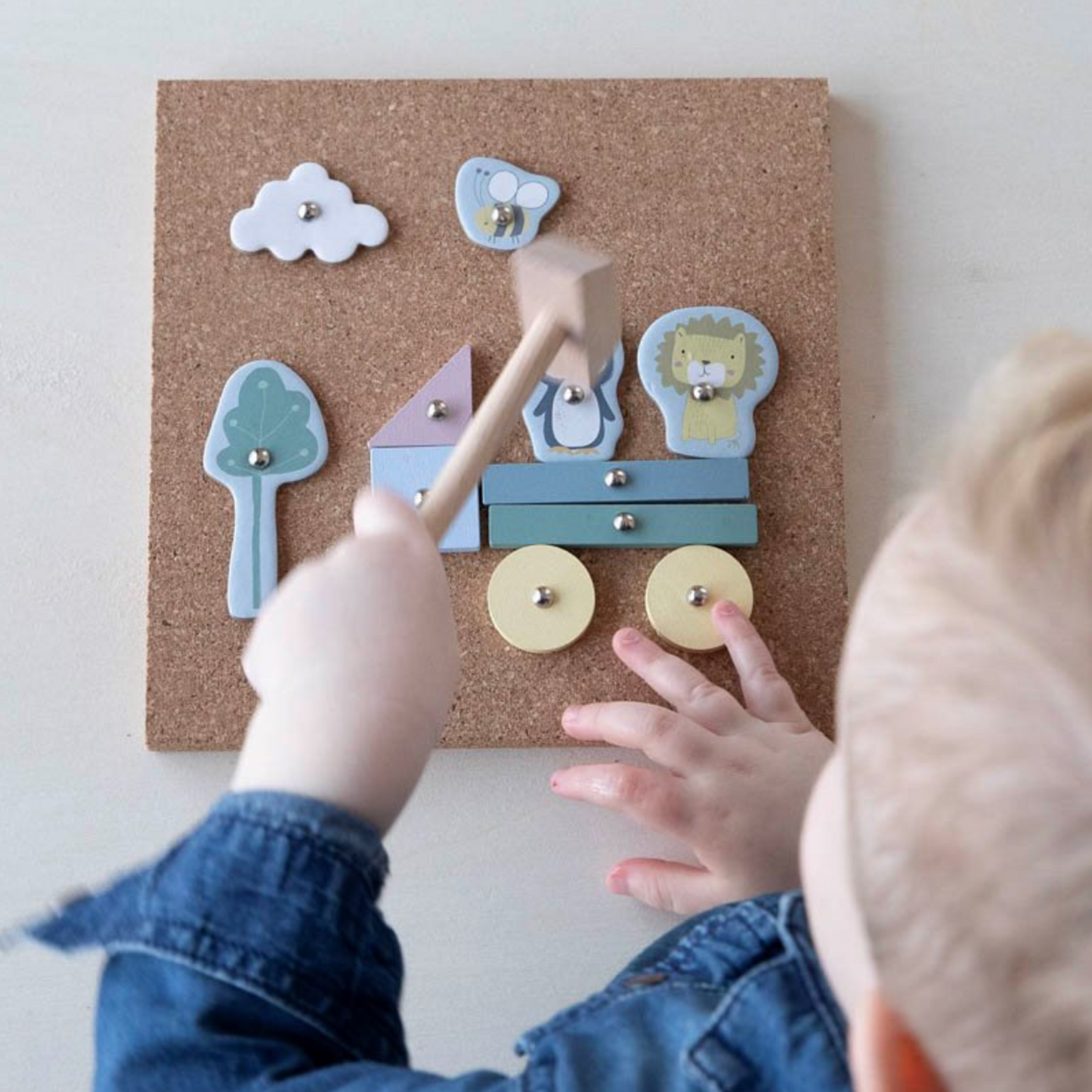 Kind spielt mit Hämmerchenspiel von Little Dutch und nagelt Holzfiguren wie Löwe, Pinguin und Zug auf Korkplatte – Spielzeug zur Förderung der Feinmotorik ab 4 Jahren, Geschenkidee von Burgfrollein