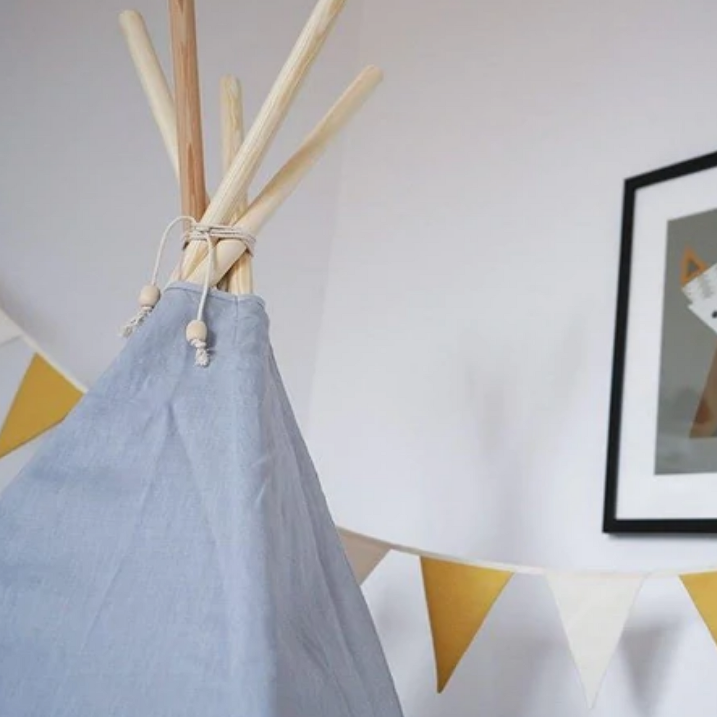 Kinderzimmer-Dekoration mit Wimpelkette in Gelb und Creme neben blaugrauem Kinder-Tipi